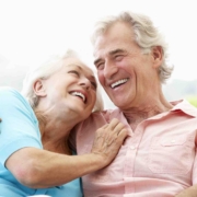 Older couple sitting and laughing, enjoying life without the worry of an enlarged prostate (BPH).
