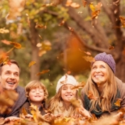Family throwing leaves in the air during the fall season.