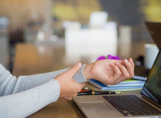 Woman holding wrist suffering from carpal tunnel syndrome, oteoarthritis, or wrist truama.