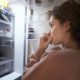 Female looking inside refrigerator contemplating what to eat